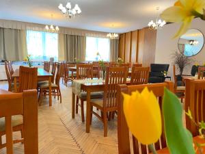 a restaurant with wooden tables and chairs and windows at Hotel U STUDÁNKY in Jablunkov