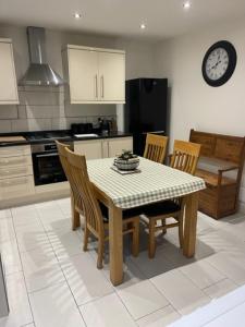 a kitchen with a table and chairs and a clock at Sleeps 8 Matlock/ Matlock Bath Pet Friendly in Matlock Bank