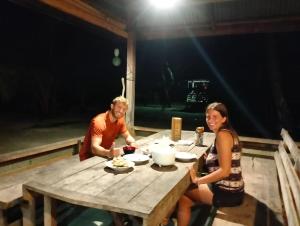 a man and a woman sitting at a wooden table at Palambak Paradise Resort Pulau Banyak in Pulau Palambakbesar