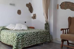 a bedroom with a bed with a green blanket and a chair at La Casina de Carcaboso in Carcaboso
