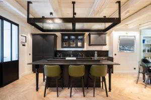 een keuken met een groot zwart eiland met stoelen bij La Madeleine in Metz