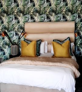 a bed with yellow pillows in front of a wall at Boutique Stay in Johannesburg