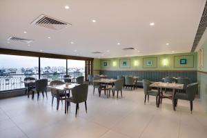 jadalnia ze stołami, krzesłami i oknami w obiekcie Lemon Tree Hotel, Rajkot w mieście Radźkot