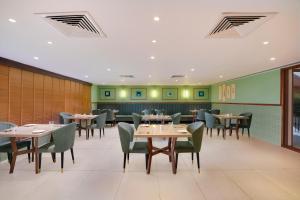 uma sala de jantar com mesas e cadeiras em Lemon Tree Hotel, Rajkot em Rajkot