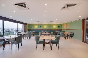 uma sala de jantar com mesas, cadeiras e janelas em Lemon Tree Hotel, Rajkot em Rajkot