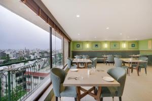 a restaurant with tables and chairs and a balcony at Lemon Tree Hotel, Rajkot in Rajkot