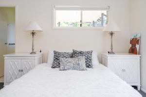 a white bed with two night stands and two lamps at E.V. - Eurong Beach Villa in K'gari Island (Fraser Island)