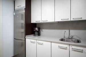La cuisine est équipée de placards blancs et d'un réfrigérateur en acier inoxydable. dans l'établissement AT157 Nova Torredembarra II, à Torredembarra