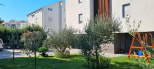 a garden with olive trees and a building at Apartman Gaby in Podstrana