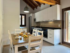 una cucina con tavolo in legno e una cucina con armadietti bianchi di Apartamentos Rurales AINARIAK a Burgui