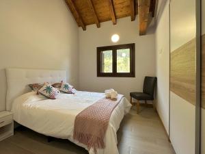 1 dormitorio con 1 cama con silla y ventana en Apartamentos Rurales AINARIAK, en Burgui