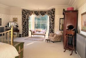 a bedroom with a bed and chairs and a window at North Ormsby Manor in Louth