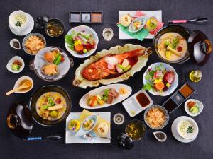 een tafel met borden en schalen van voedsel bij Kameyama Onsen Hotel in Kimitsu