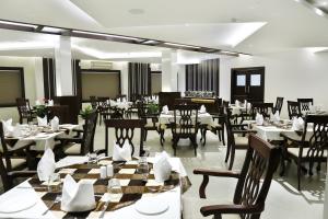 a restaurant with tables and chairs in a room at Rydges Inn in Kottakkal