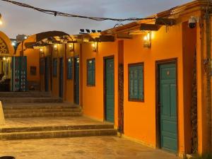 um edifício laranja com portas verdes e escadas em Fenti Nubian Resort em Aswan