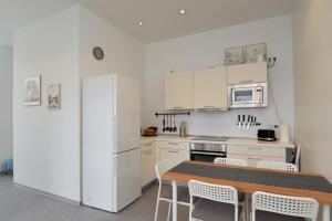 a white kitchen with a table and a refrigerator at Gästewohnung Milan in Suhl