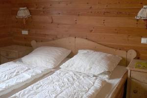 a bed in a wooden room with two pillows at Ferienhaus Nr 14, Typ A, Feriendorf Jägerpark, Bayerischer Wald in Viechtach