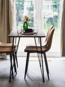 ein Tisch mit einer Flasche Wein und zwei Stühlen in der Unterkunft Comfy Spacious Home Near Preston City Centre - Sleeps 6 in Samlesbury