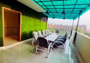 una mesa y sillas en un balcón con una pared verde en Hotel Deluxe Johar Town Lahore, en Lahore