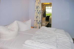 uma cama com lençóis brancos e almofadas num quarto em Ferienwohnung De Keef em Dorum