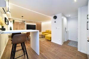 a kitchen and living room with a white counter and a yellow couch at Optima Apartment Zagreb - Spacious Central Stay in Zagreb +11 photos