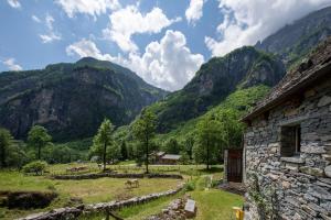 a stone building in a field with mountains in the background at Rustico Savinera - Happy Rentals in San Carlo