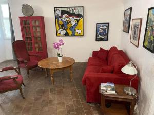 a living room with a red couch and a table at Magnifique gîte 75M2 avec terrasse 30m2, piscine, terrain de pétanque, et jardin en Cévennes in Meyrannes