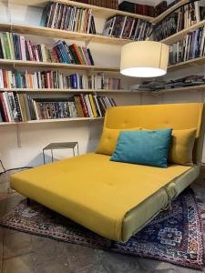 a large yellow bed in a room with books at Magnifique gîte 75M2 avec terrasse 30m2, piscine, terrain de pétanque, et jardin en Cévennes in Meyrannes