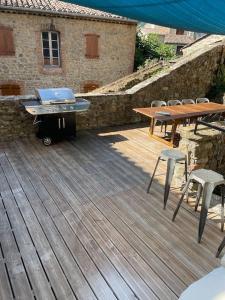 a grill and tables and chairs on a wooden deck at Magnifique gîte 75M2 avec terrasse 30m2, piscine, terrain de pétanque, et jardin en Cévennes in Meyrannes