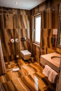 bagno con pareti in legno, servizi igienici e lavandino di Senator Hotel a Tirana