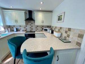 a kitchen with a counter and two blue chairs at Seagull Leigh Cottages in Seaton