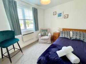 a bedroom with a bed and a chair and a window at Seagull Leigh Cottages in Seaton