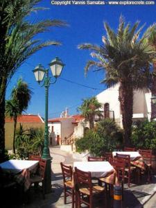 a restaurant with tables and a street light and palm trees at Fairytale apartment in Agios Ioannis