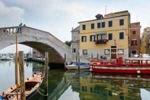 a bridge over a river with boats and buildings at Maison Sophie in Chioggia