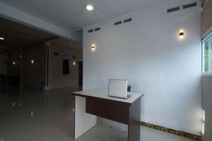 Habitación blanca con escritorio y ordenador portátil. en OYO 92924 Kalista Guest House Syariah, en Pekanbaru