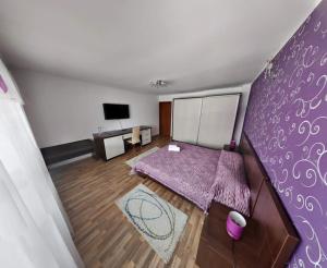 a living room with a purple wall with a bed at Casa 1 Mai, Parcare in curte in Râmnicu Vâlcea