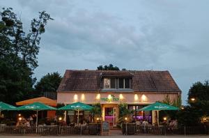 a restaurant with green umbrellas in front of a building at Pension Mojito Senftenberg in Senftenberg