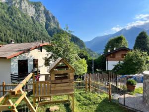 a house with a playground in front of a mountain at Baitèl de Sòt e Sura - Appartamenti in Gromo