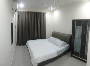 1 dormitorio con 1 cama con sábanas y almohadas blancas en KITAKAYA Homestay Kota Bharu - 8 Pax, en Kota Bharu