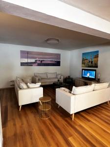 a living room with two white couches and a tv at PFA Hotel - Isola d'Elba in Cavo