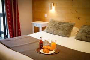 a bed with a tray of food and drinks on it at Hotel Le Faranchin in Villar-dʼArène