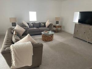 a living room with two couches and a flat screen tv at Luxury Barn near Soho Farmhouse in Middle Barton