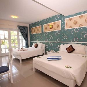 - une chambre avec 2 lits et un mur vert dans l'établissement MUINE SUN AND SEA RESORT & GLAMPING, à Mui Ne