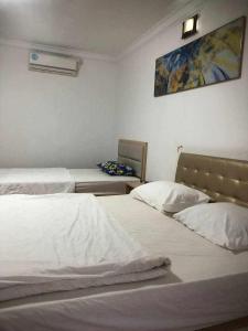 a bedroom with two beds and a painting on the wall at Sea Inn Guesthouse Sihanoukville in Sihanoukville