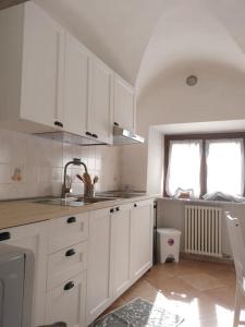 cocina con armarios blancos, fregadero y ventana en appartamento in Borgo storico., en Pontremoli