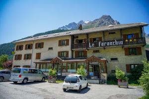 a large building with cars parked in a parking lot at Hotel Le Faranchin in Villar-dʼArène