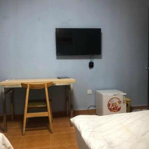 a room with a desk and a television on a wall at Sea Inn Guesthouse Sihanoukville in Sihanoukville