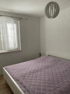 een slaapkamer met een bed met een paars dekbed bij Apartments Đurđa, Sabunike in Privlaka