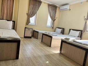 Cette chambre comprend trois lits et deux fenêtres. dans l'établissement Ikat Terrace, à Boukhara