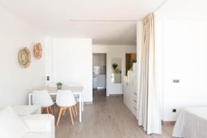 a white apartment with white furniture and a dining room at Loft Los Caracoles in Palamós